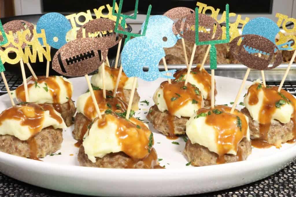 front view of super bowl meatloaf bites with mashed potatoes and gravy and fun football-themed toothpicks