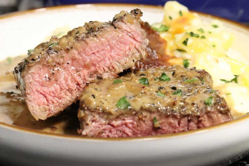 valentines dinner for two - steak au poivre with potatoes au gratin: steak cut in half and medium rare with sauce and parsley