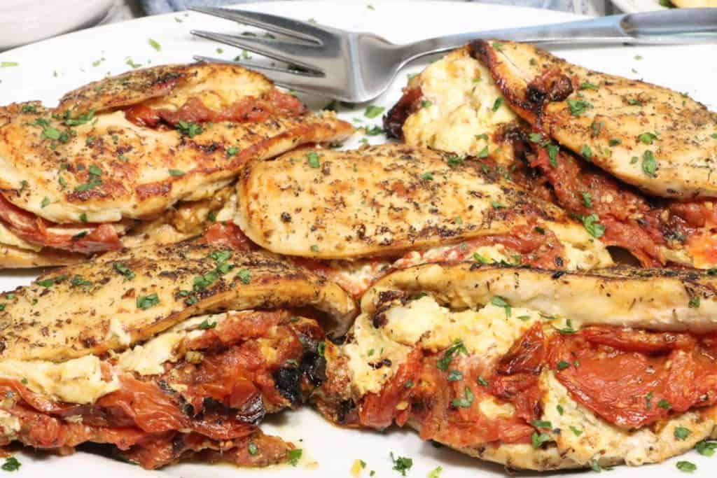 Stuffed Chicken Breast with Roasted Tomatoes, Goat Cheese and Leeks: head on view of platter of chicken garnished with chopped parsley