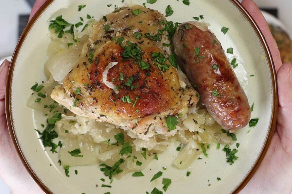 a closer look at one portion of chicken sauerkraut and sausage garnished with fresh parsley