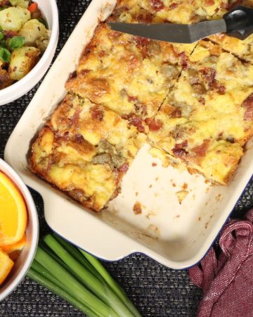 overhead table view of fantastic meaty breakfast casserole with a side of home fries, scallion and orange wedges