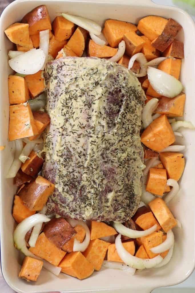 mustard and herb covered pork roast with sweet potatoes and onion
