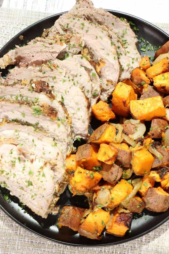 Cheap and easy dinner dijon pork roast and sweet potatoes on a serving plate garnished with fresh parsley