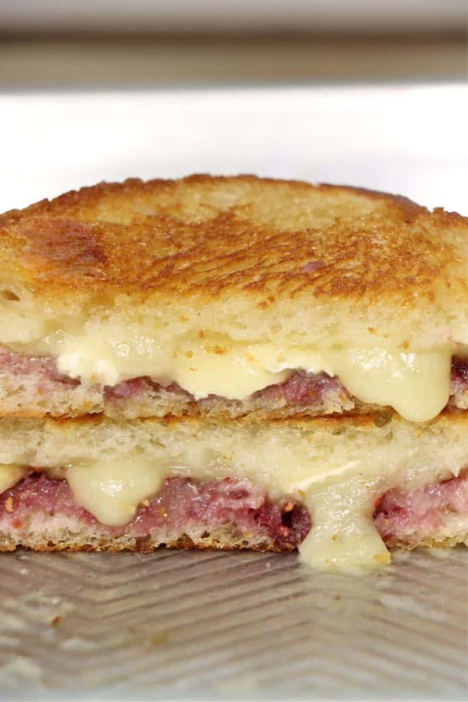 close up view of crunchy raspberry brie grilled cheese with melty cheese on a sheet pan