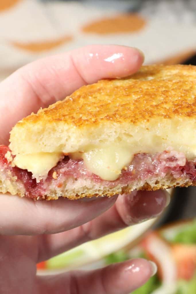 holding one half of raspberry brie grilled cheese