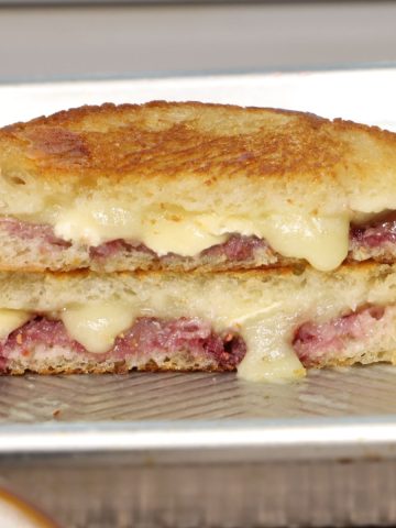 crunchy raspberry brie grilled cheese stacked on top of each other on a sheet pan