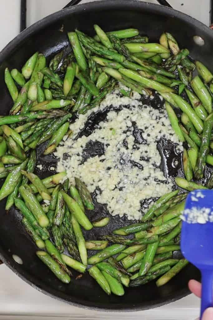 overhead view of cooking the chopped asparagus and garlic in a saute pan
