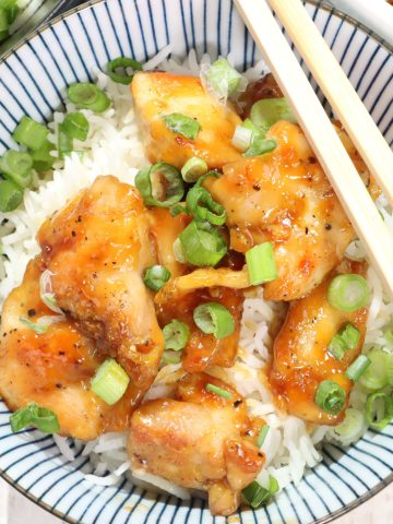overhead view of a bowl of honey soy chicken over basmati rice garnished with scallions
