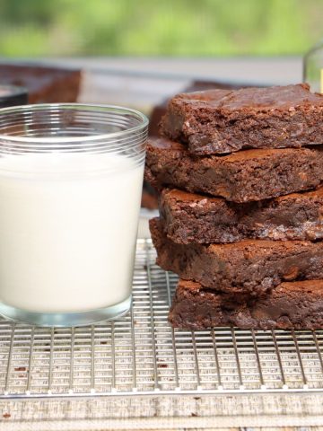ina garten's sheet pan brownies aka outrageous brownies stacked in a pile next to a glass of milk