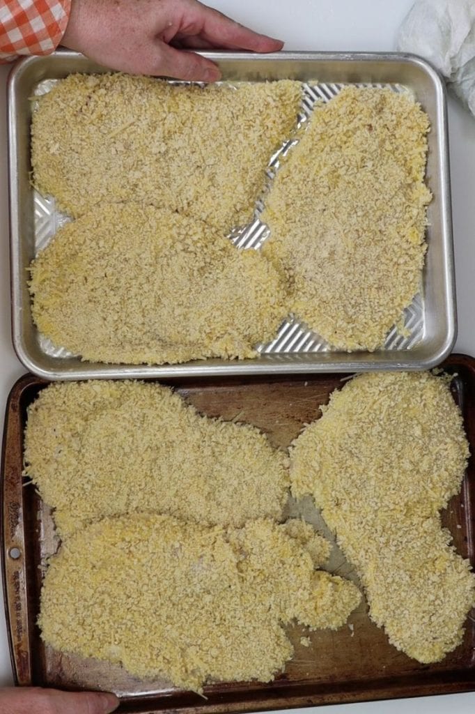 two small sheet pans with breaded chicken cutlets