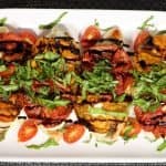 pan seared chicken caprese with roasted tomatoes and fresh basil on a serving platter with balsamic glaze