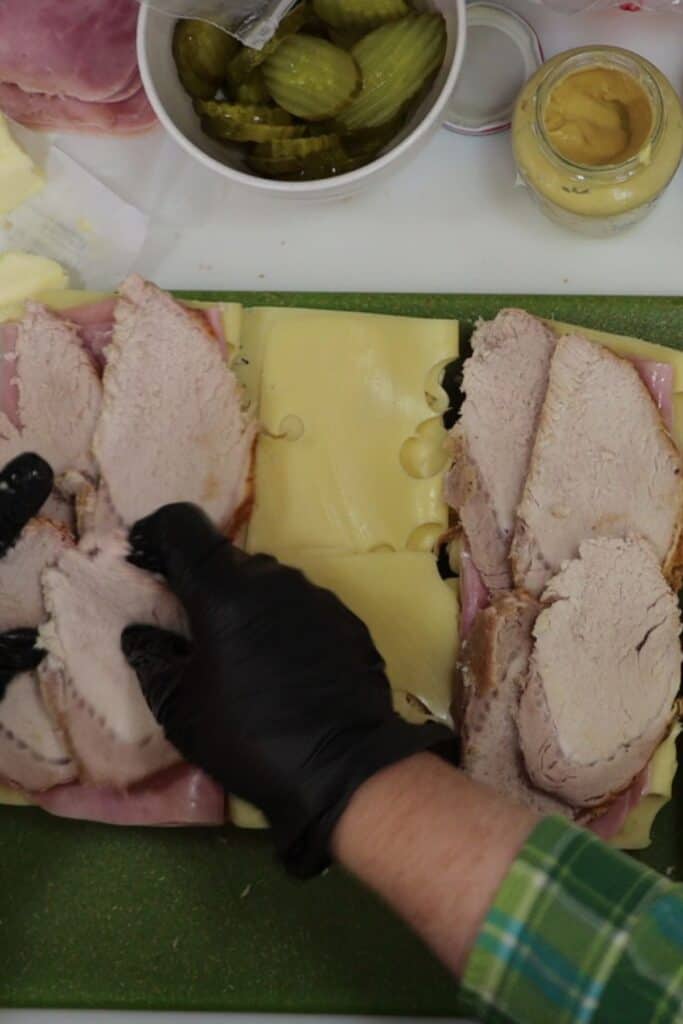 adding the sliced roasted pork to the cuban sandiwches