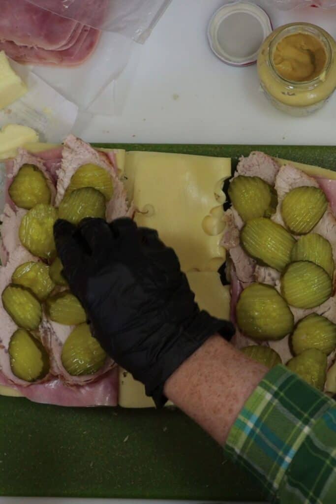 placing dill pickle rounds on top of pork