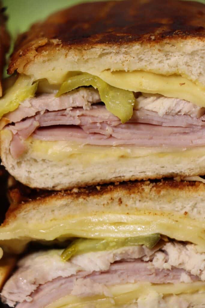 close up look at the stack of pork, ham, cheese, pickles and mustard inside this easy pressed cuban sandwich
