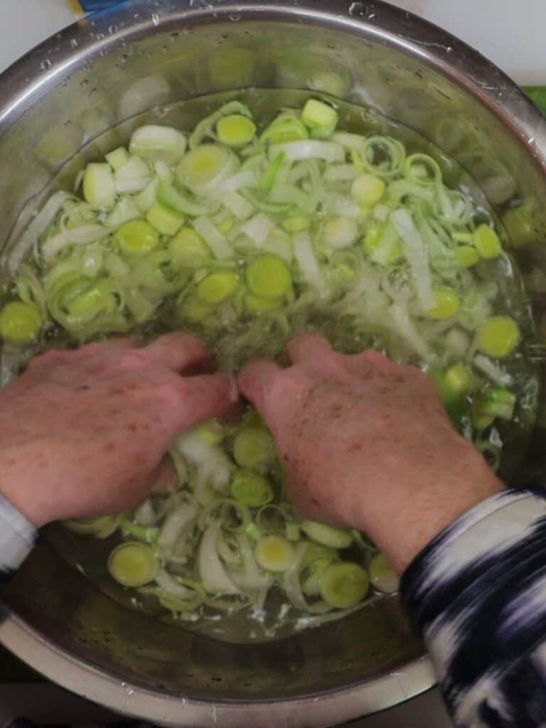 overhead view of sliced leeks being rinsed in a large bowl