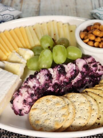 front view of affordable walmart cheese tray with brie, gouda, pepperjack, blueberry goat cheese, honey roasted peanuts, crackers and grapes