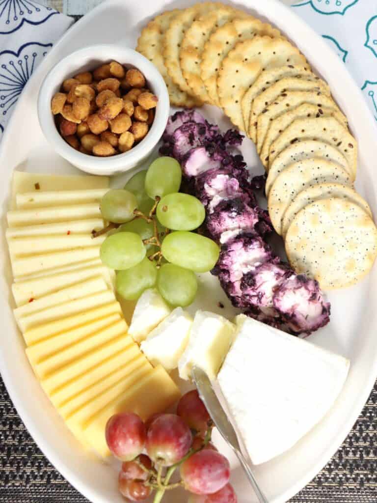 overhead view of affordable walmart cheese tray with gouda, pepperjack, peanuts, crackers, grapes, brie, and blueberry goat cheese
