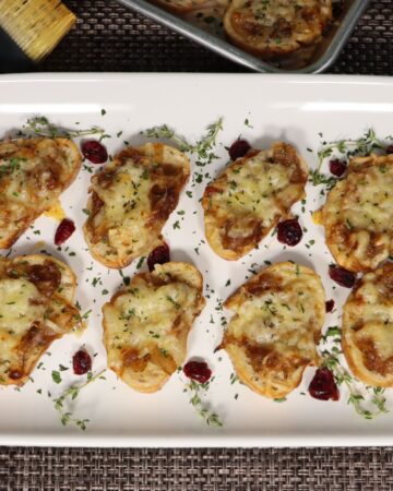 french onion crostini on a platter with thyme and craisin garnish