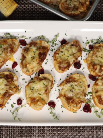 french onion crostini on a platter with thyme and craisin garnish