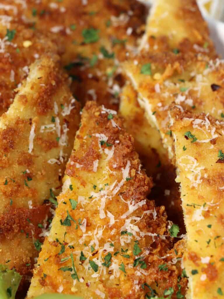 close up look at crunchy cheddar chicken cutlets garnished with parmesan cheese and parsley
