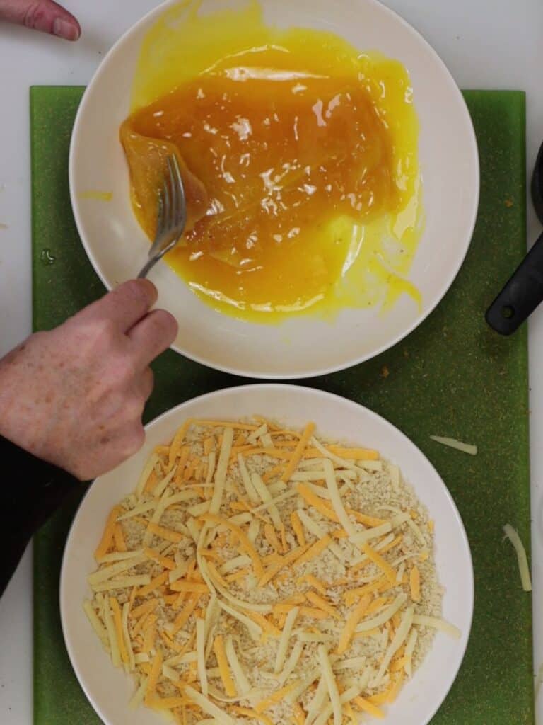 dredging chicken cutlet in egg yolk and bread crumbs with cheddar cheese