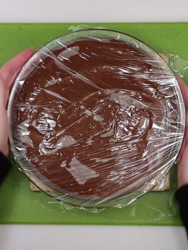 covering the chocolate cream pie with plastic wrap to set and chill in fridge