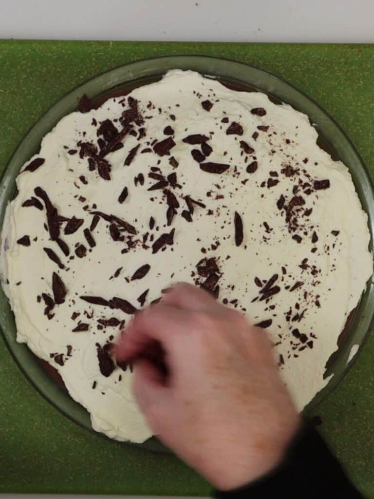 adding the chocolate shavings to the top of the chocolate cream pie with graham cracker crust