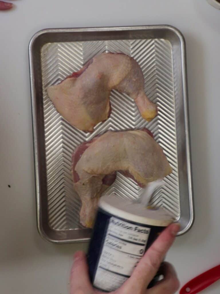 overhead view of seasoning chicken with salt and pepper
