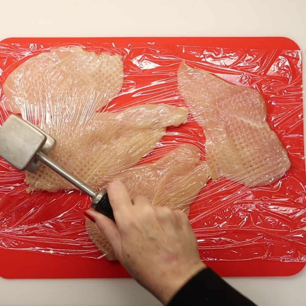 pounding the chicken cutlets with a kitchen mallet