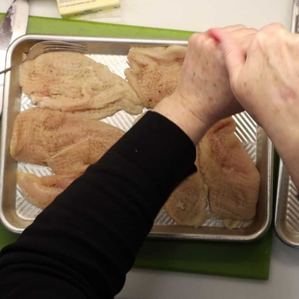 seasoning the chicken with salt and pepper