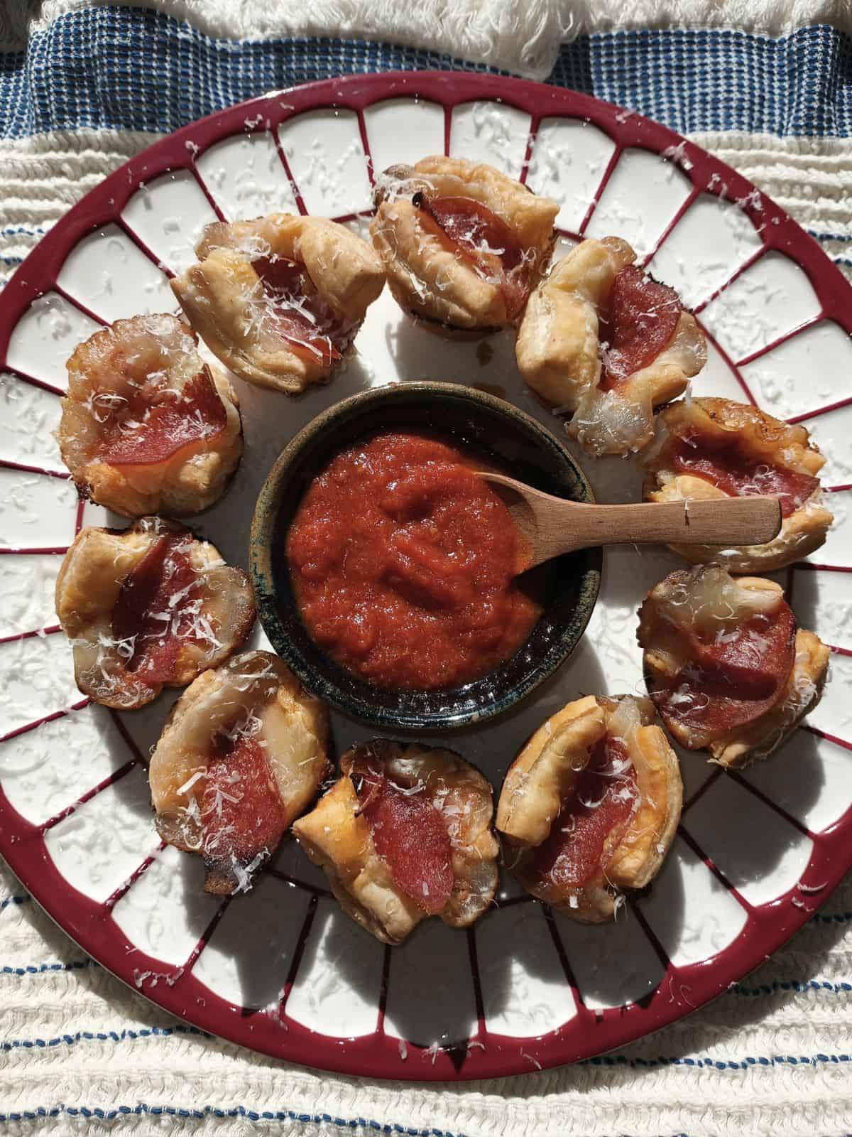 overhead view of pepperoni pizza puffs with grated cheese garnish and extra sauce on the side