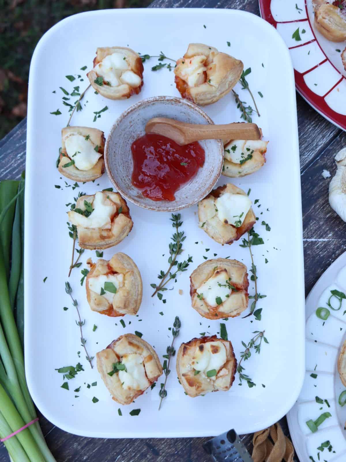 overhead view of red pepper jelly and cream cheese puffs garnished with fresh thyme sprigs