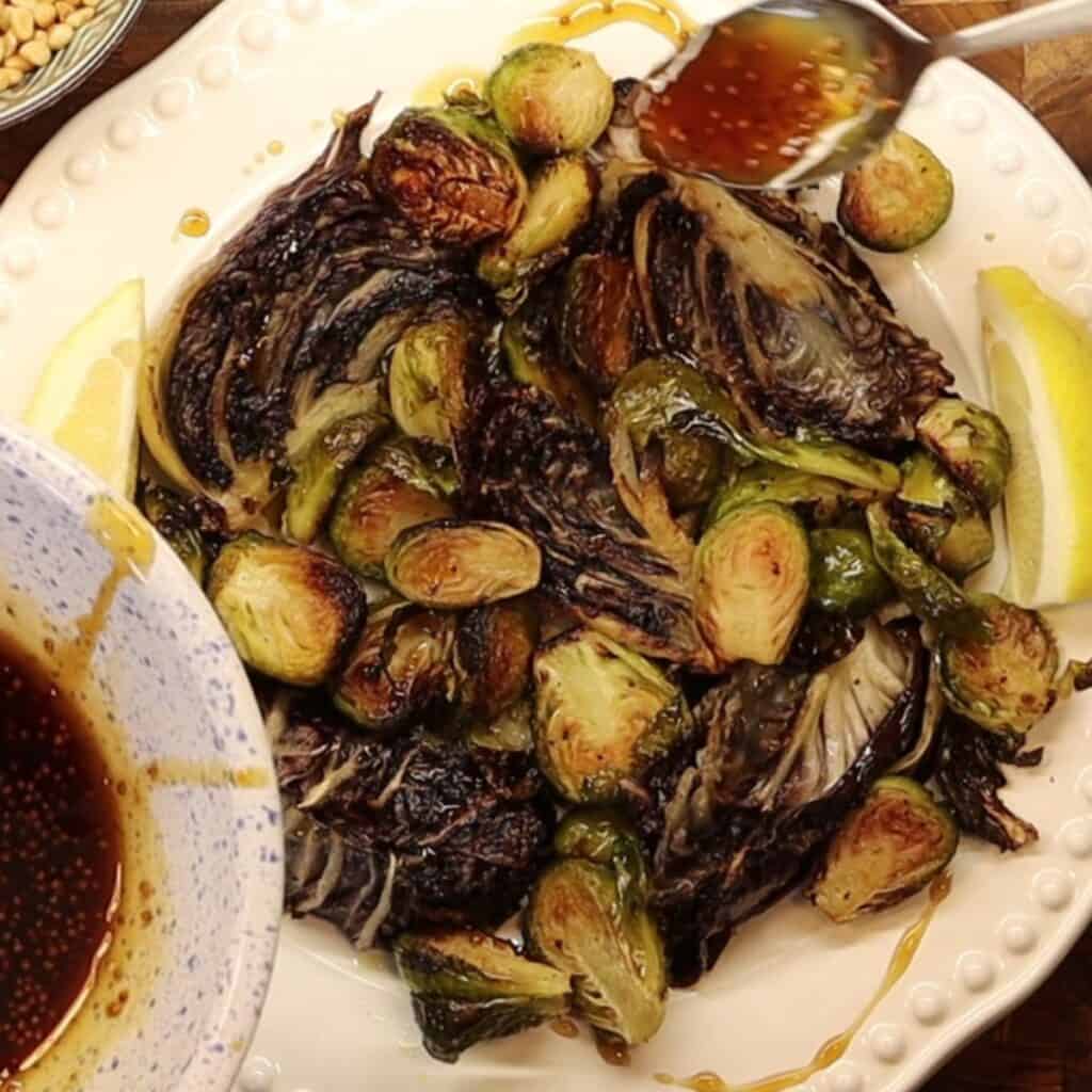 assembling plate with roasted brussels sprouts and radicchio - topping with maple mustard drizzle
