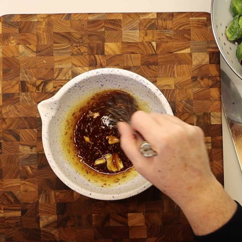mixing the maple mustard drizzle for the brussels sprouts and radicchio