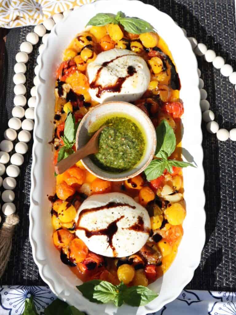overhead view of roasted cherry tomatoes with smashed garlic and burrata with basil and balsamic glaze