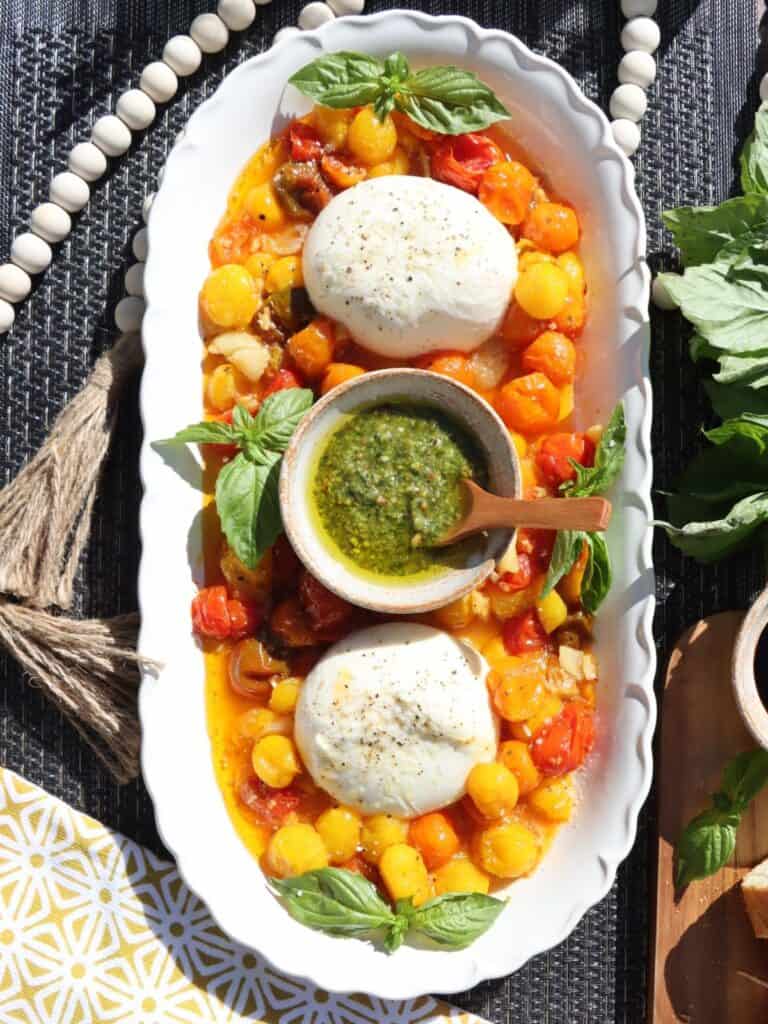 close up view of roasted cherry tomatoes with smashed garlic and burrata