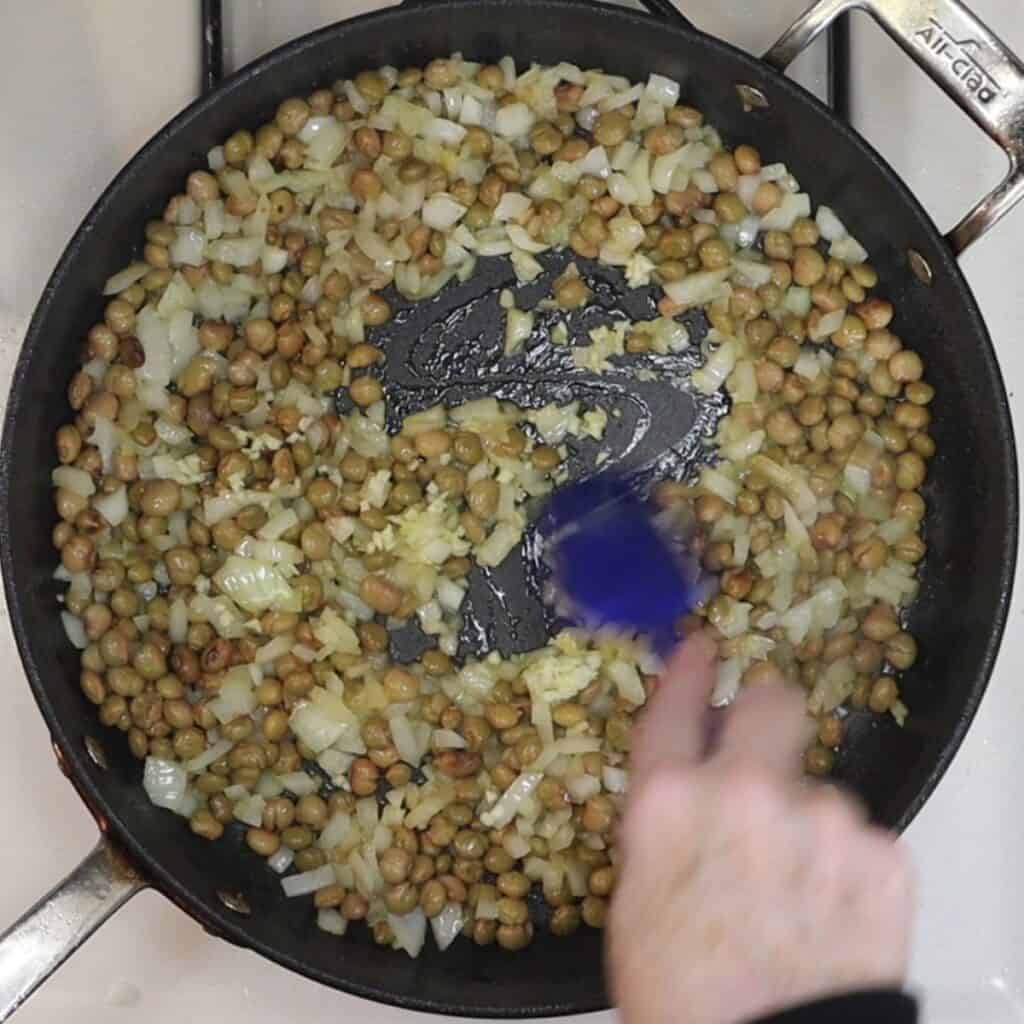 cooking onions, pigeon peas and garlic in a pan