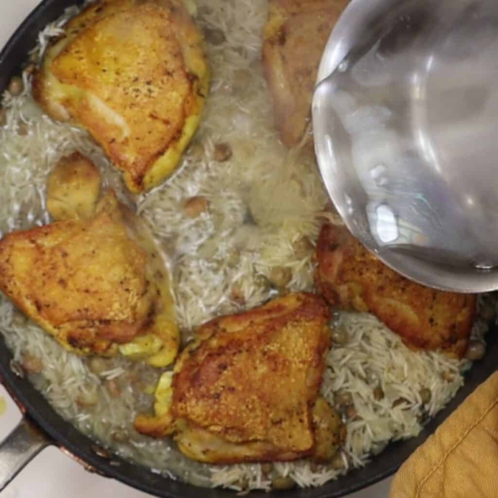 adding chicken and boiling water to the pan