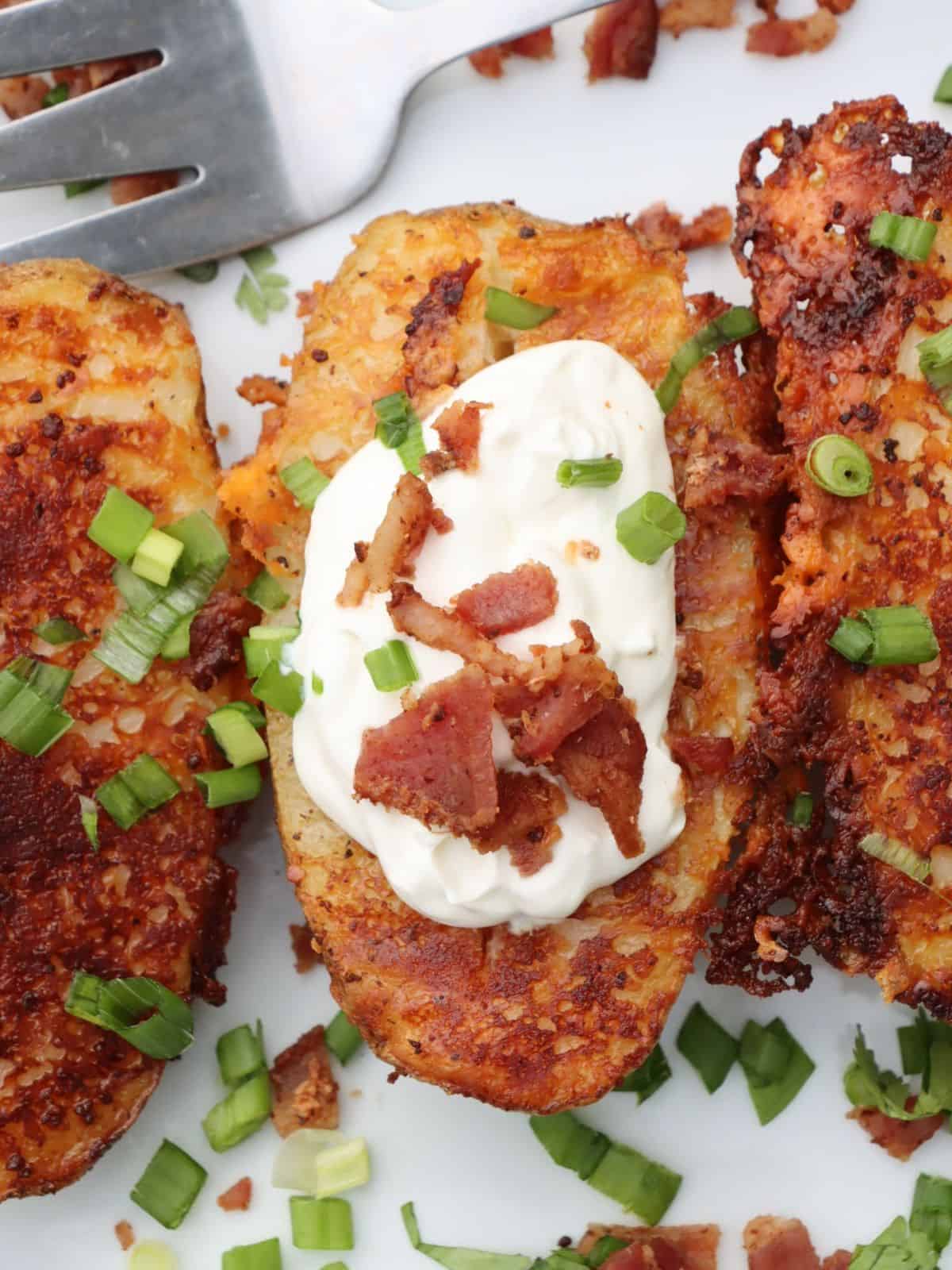 close up view of quick and easy baked potato halves with bacon, sour cream and scallions