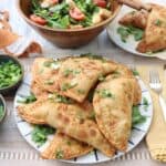 puerto rican style chicken empanadas on a plate with salad in background