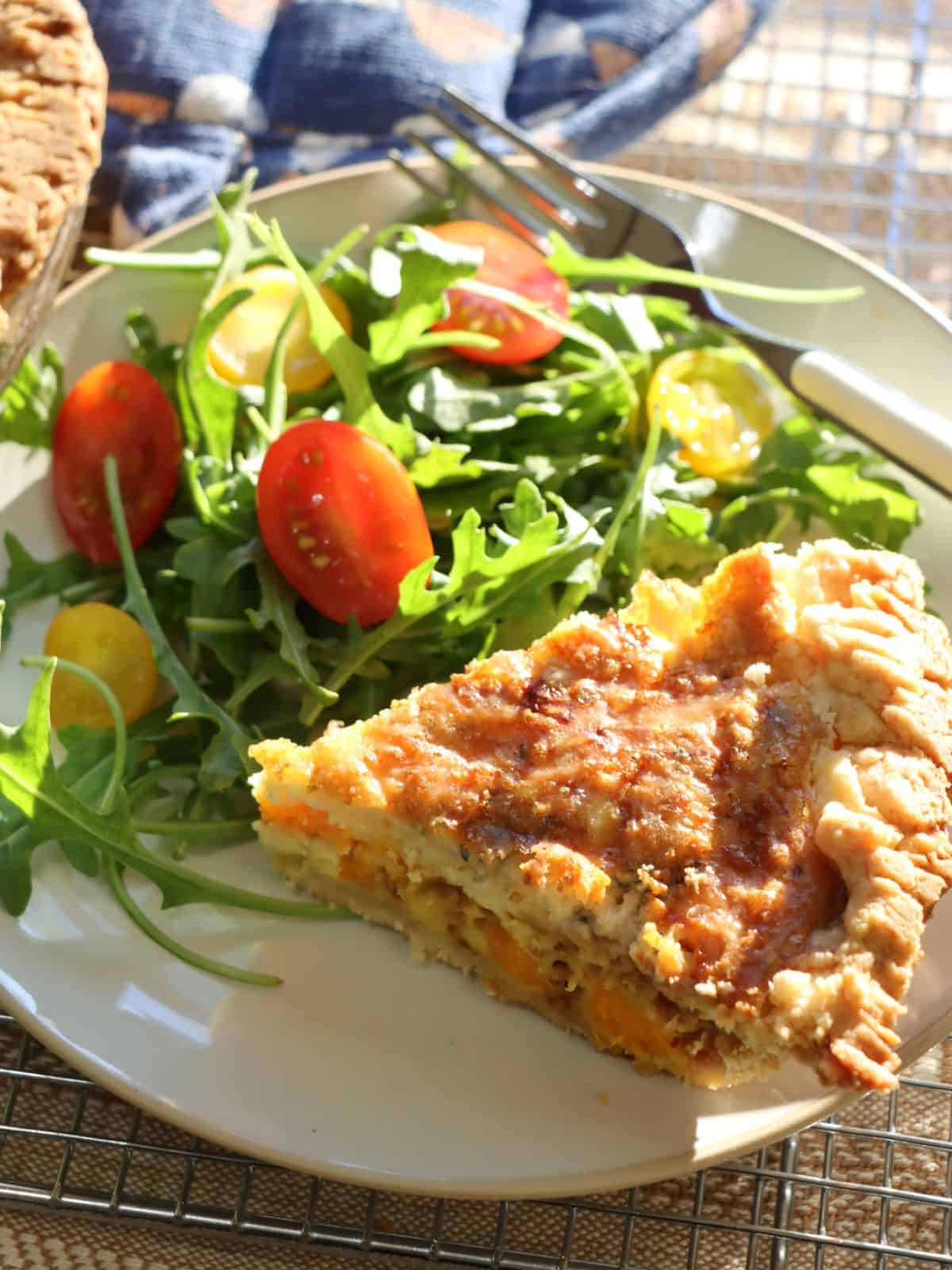 one slice of sweet potato quiche with bleu cheese and caramelized onions on a plate with a salad