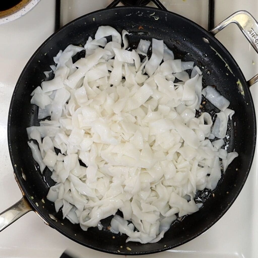 fresh wide rice noodles in the pan ready to pad see ew assembly