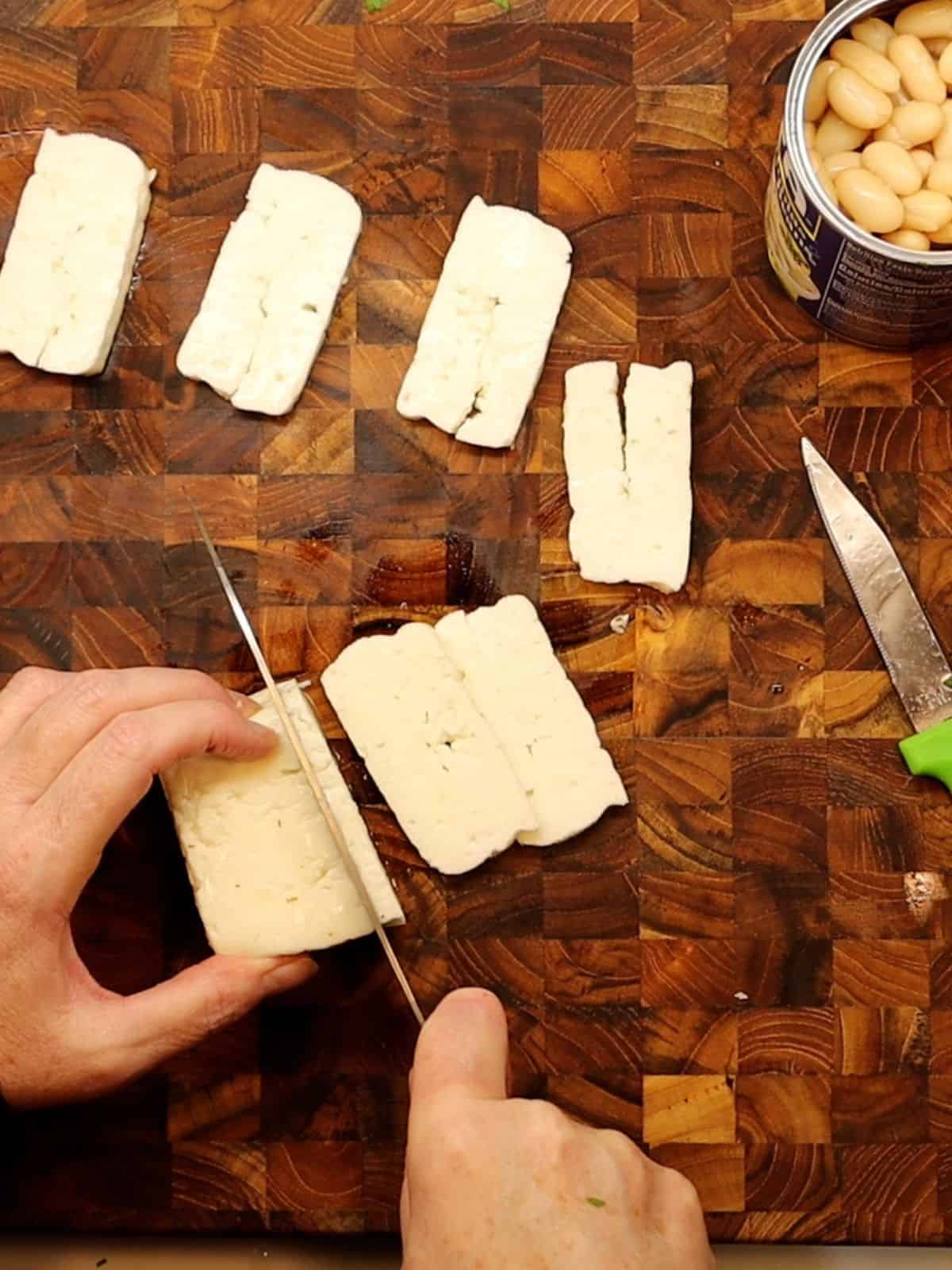 slicing halloumi cheese on a cutting board with cannelini beans to the right