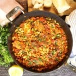 overhead view of NY Times Crispy Halloumi with Tomatoes and White Beans with lemon and french bread in the background.