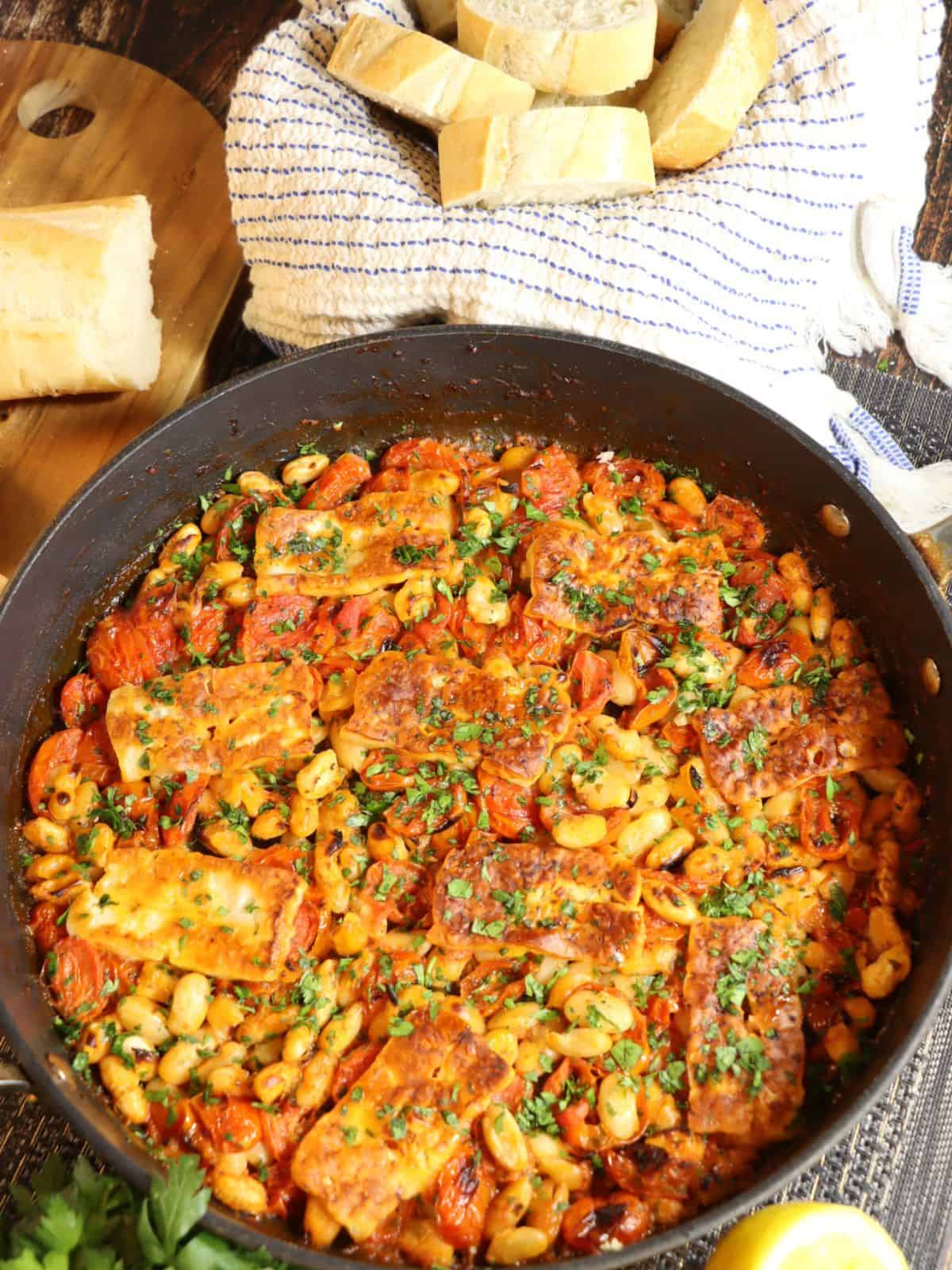 full pan of NY Times Crispy Halloumi with Tomatoes and White Beans with bread basket in background