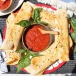 pepperoni pizza roll-ups on a plate with marinara sauce in the middle