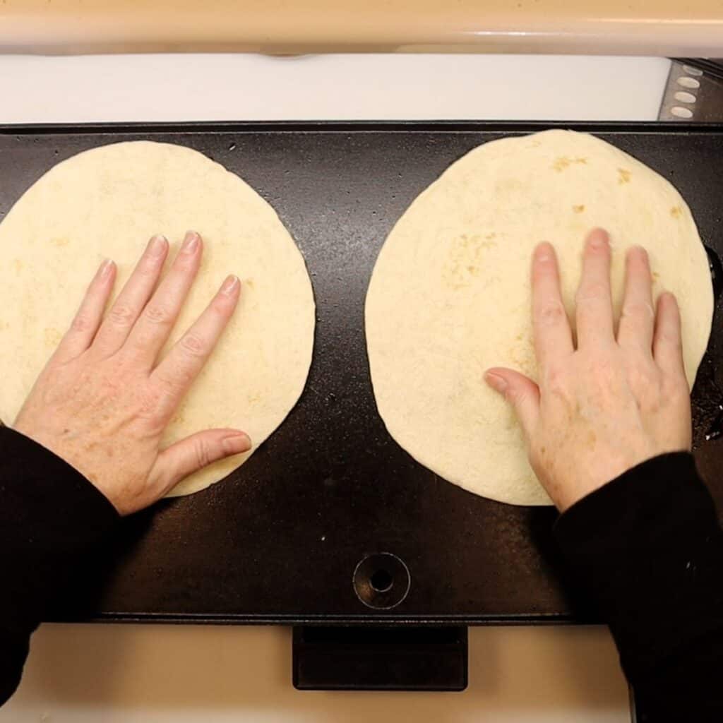 placing flour tortillas on top of cheese and pepperoni for pepperoni pizza roll-ups