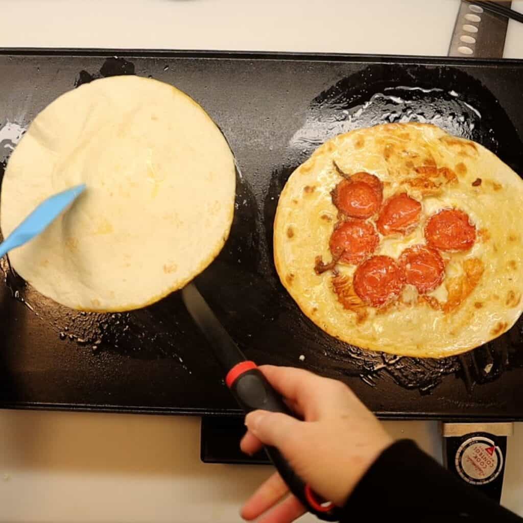 flipping the pepperoni tortilla pizza roll-ups