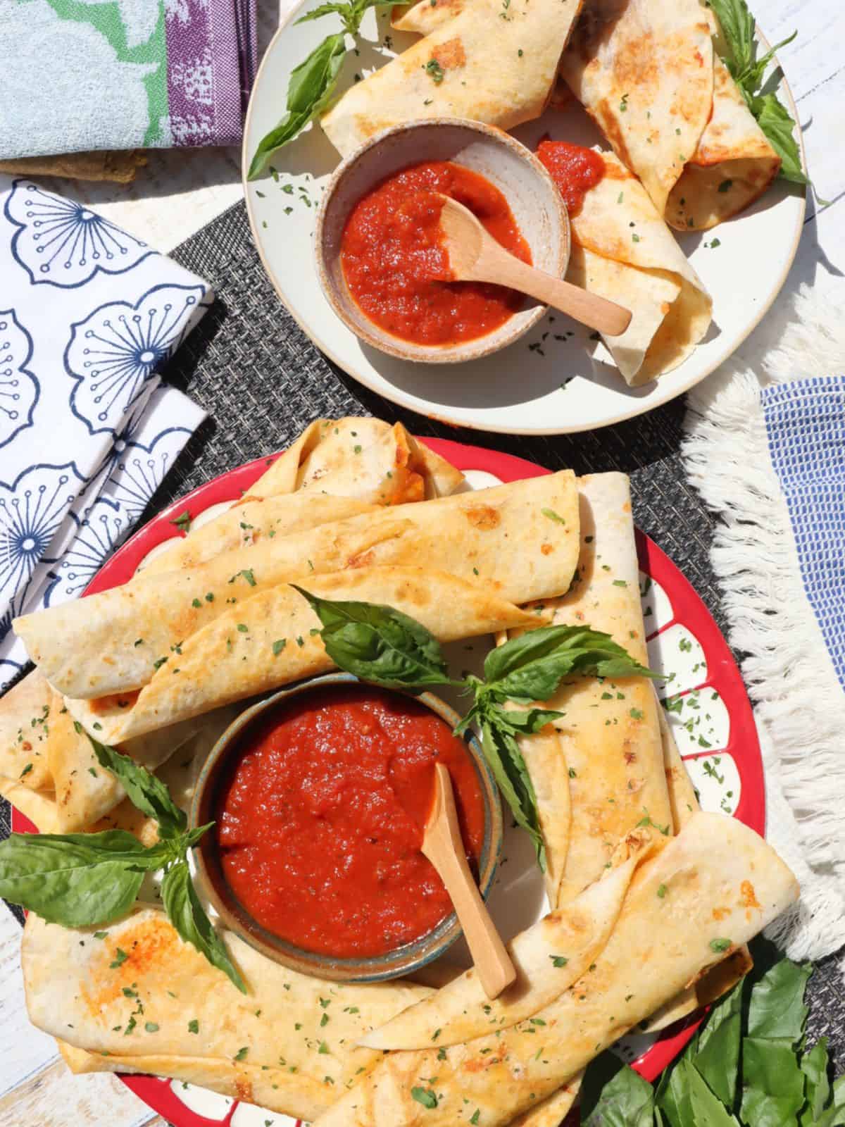 overhead table view of pepperoni pizza roll-ups on a plate plus one individual portion