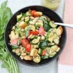 overhead view of warm zucchini bean salad with croutons, basil and citrus vinaigrette
